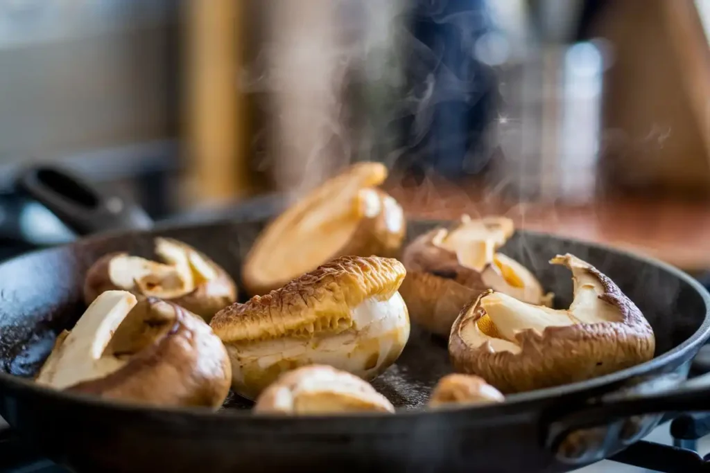 Close-up of Chicken of the Woods mushroom cooking in a skillet with steam rising.