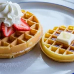 A side-by-side comparison of a thick Belgian waffle with deep pockets, topped with cream and berries, versus a thin regular waffle with shallow pockets, topped with butter and syrup.