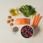 A flat lay of nutrient-rich foods for an ALS diet plan, including salmon, olive oil, berries, and walnuts, symbolizing supportive nutrition.